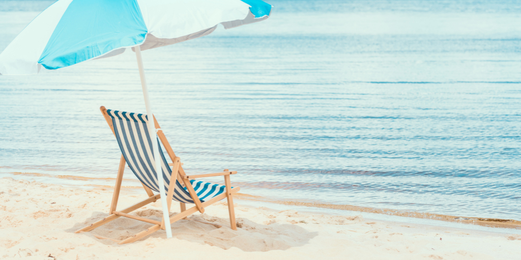 Chair and umbrella on the beach by water in the summer.