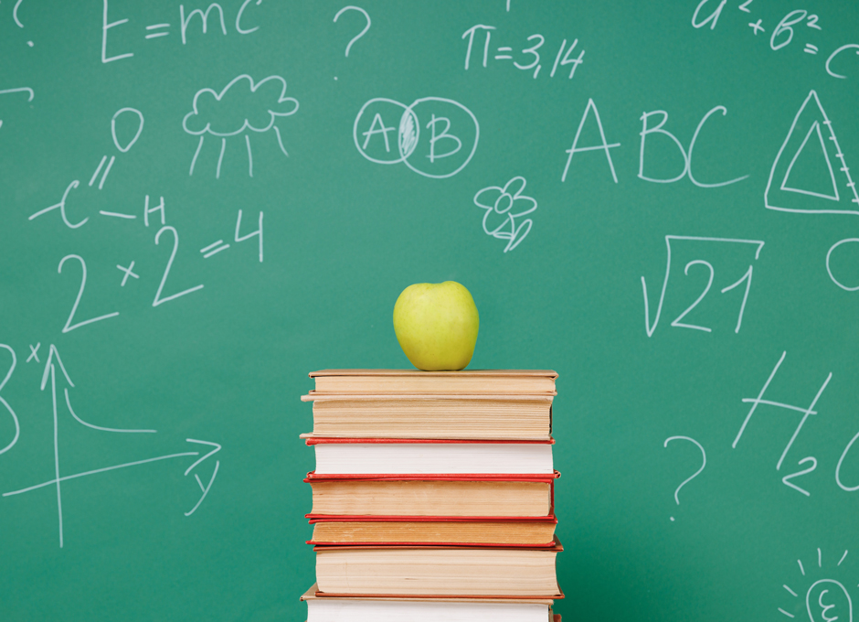 A classroom with a chalkboard, books, and an apple