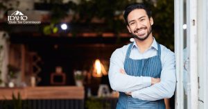 Happy business owner standing in front of his store